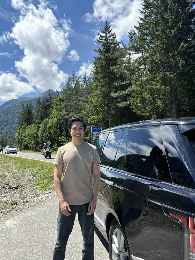 Michael beside his car at the Austrian border, mountains behind